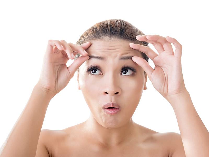 Frau runzelt Sirn und Sirnfalten sind sichtbar